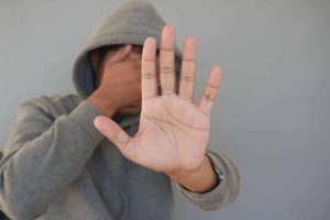a hooded man covering his face sores from drugs