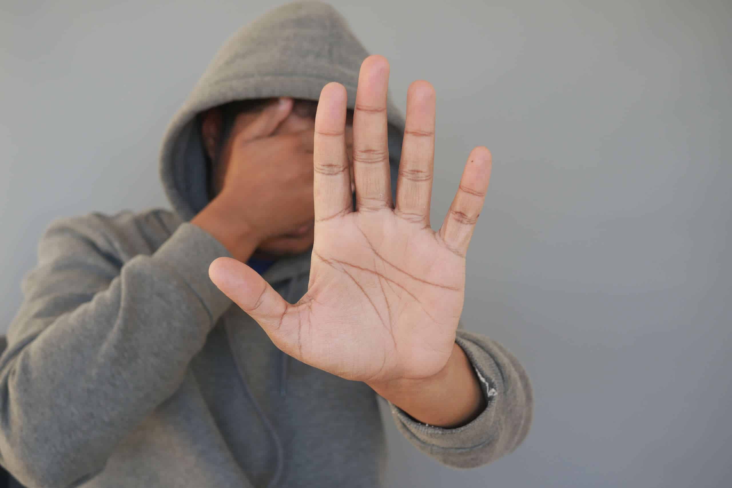 a hooded man covering his face sores from drugs