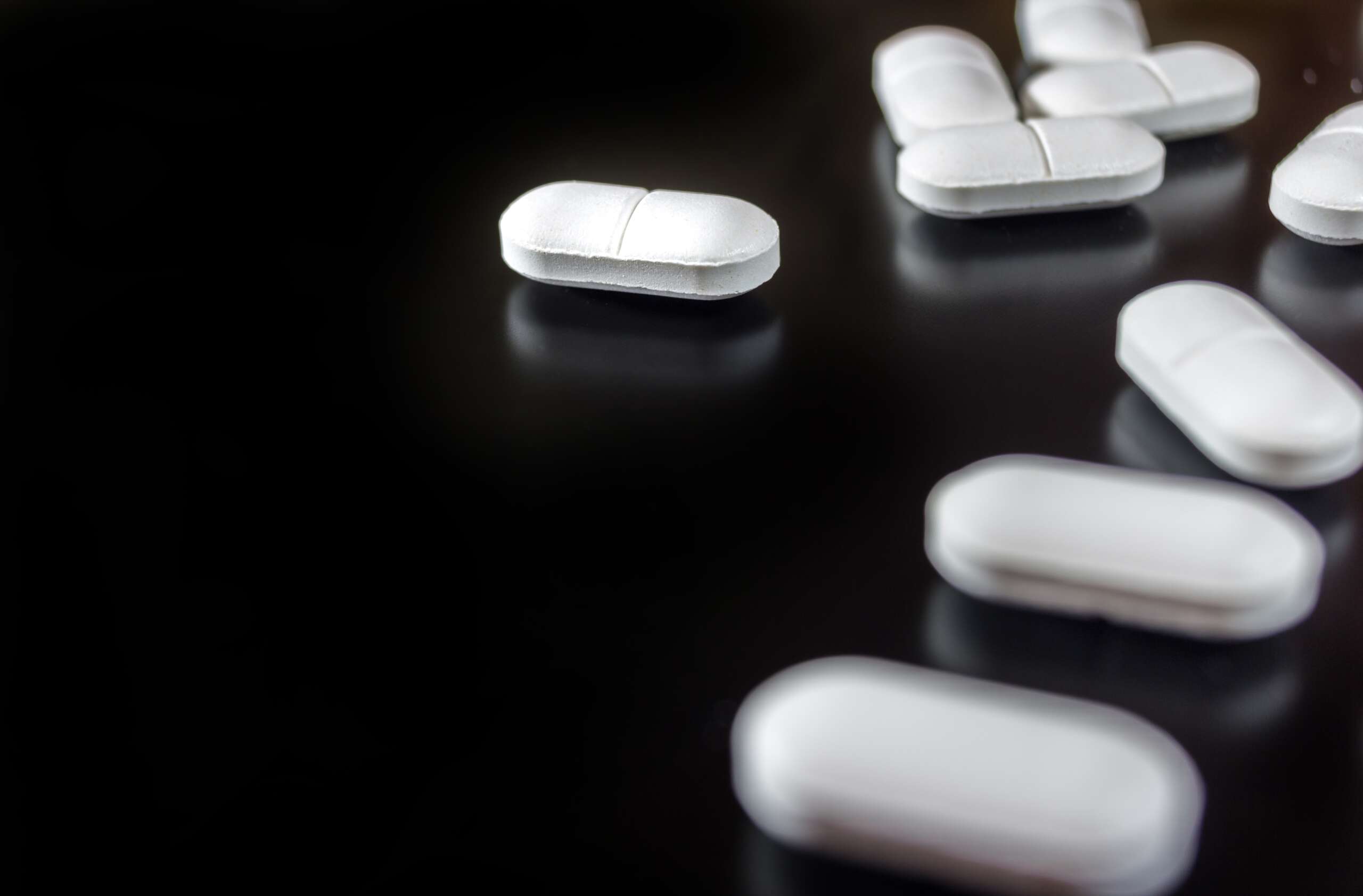 white pills on a black background begging the question "can hydrocodone cause anxiety?"