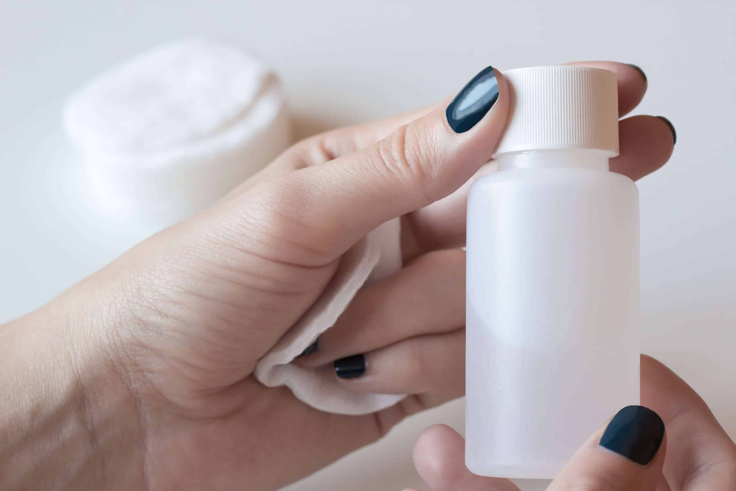 a woman holding a bottle of nail polish remover to show what acetone is used for in drugs